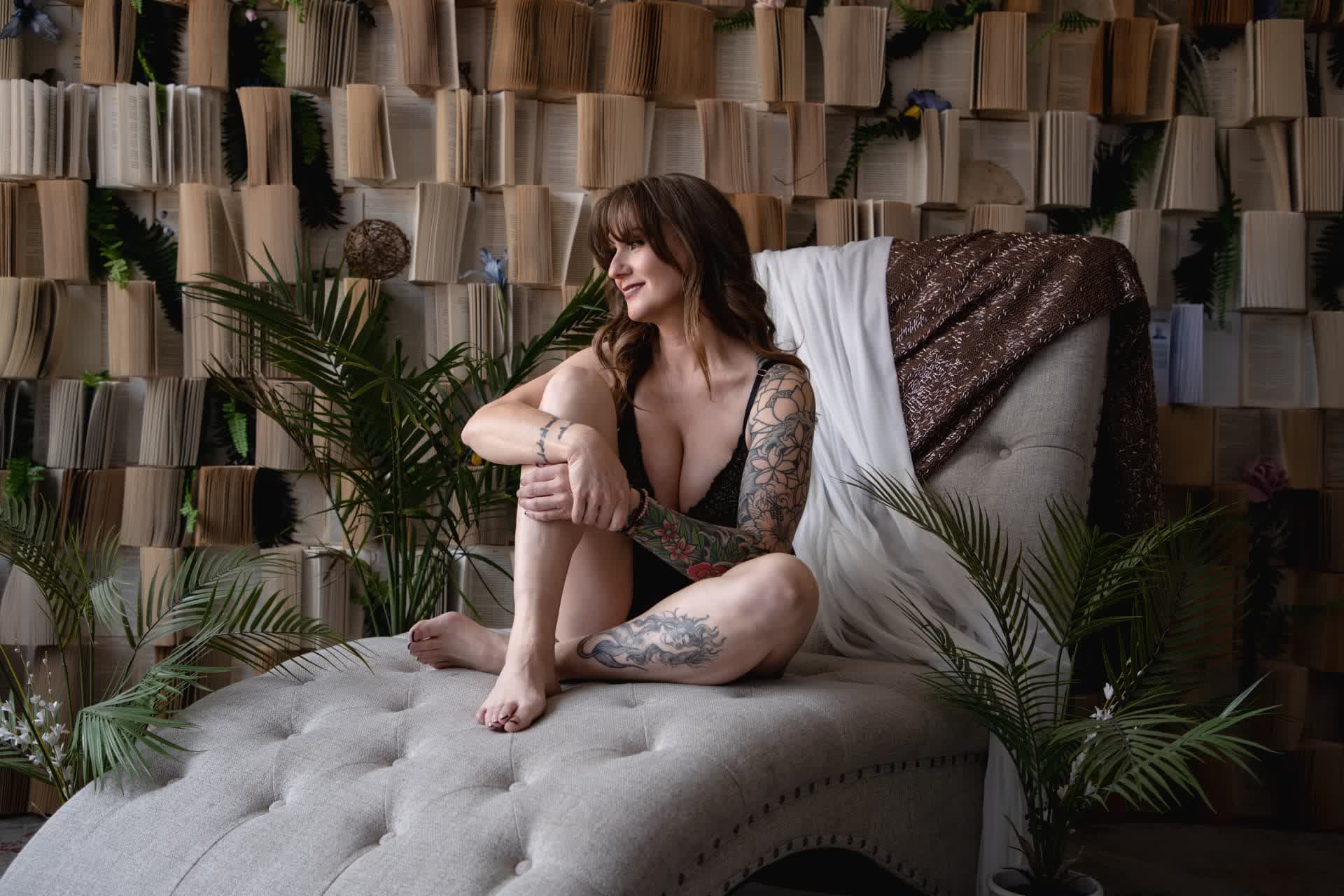 Woman seated on a tufted chaise in a book-wall studio
