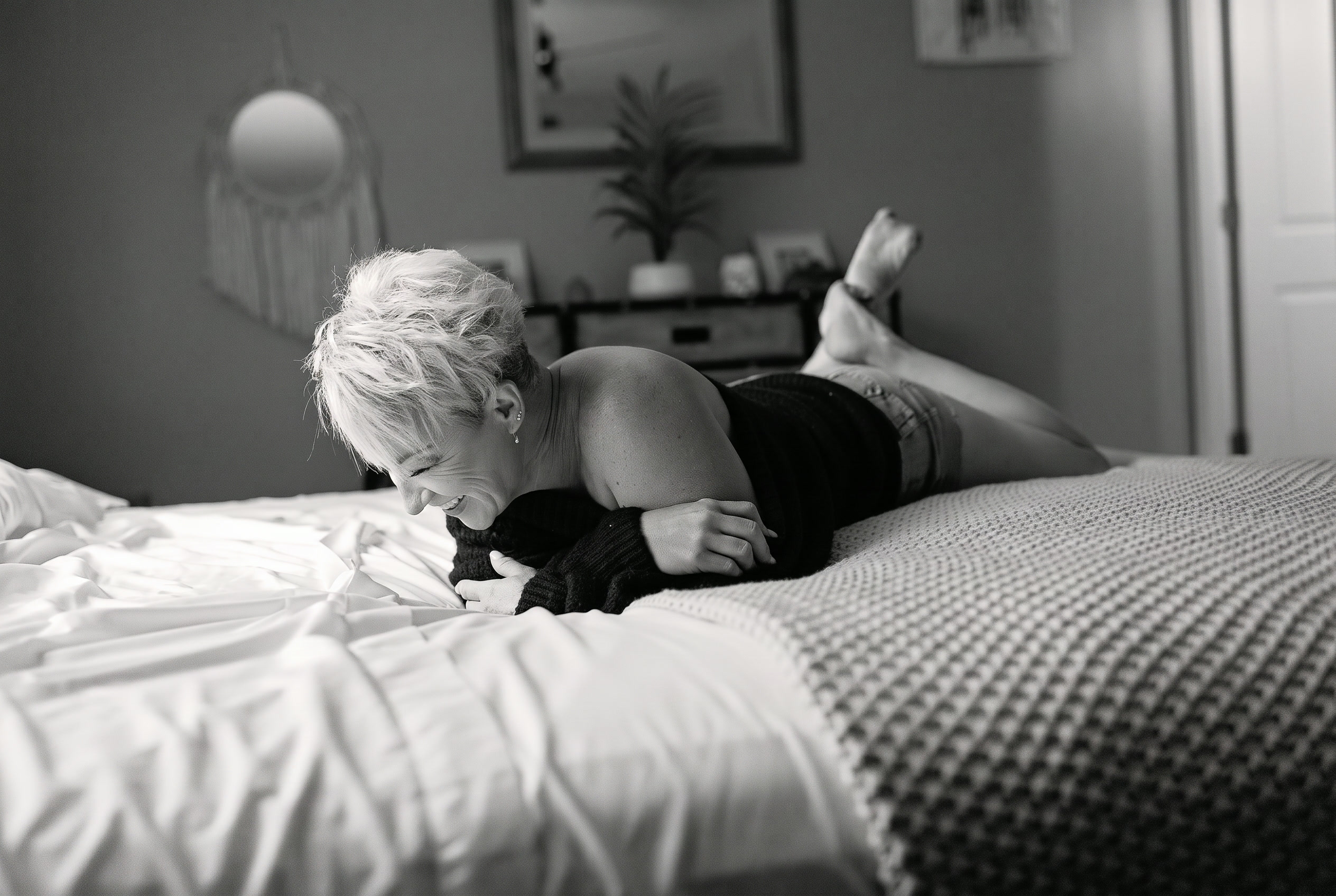 Client laughing on a bed in black and white portrait